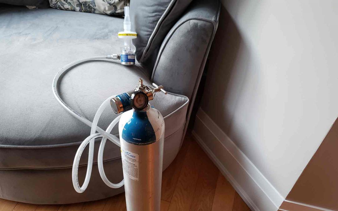 Nitrous oxide canister with tubing in front of gray chair